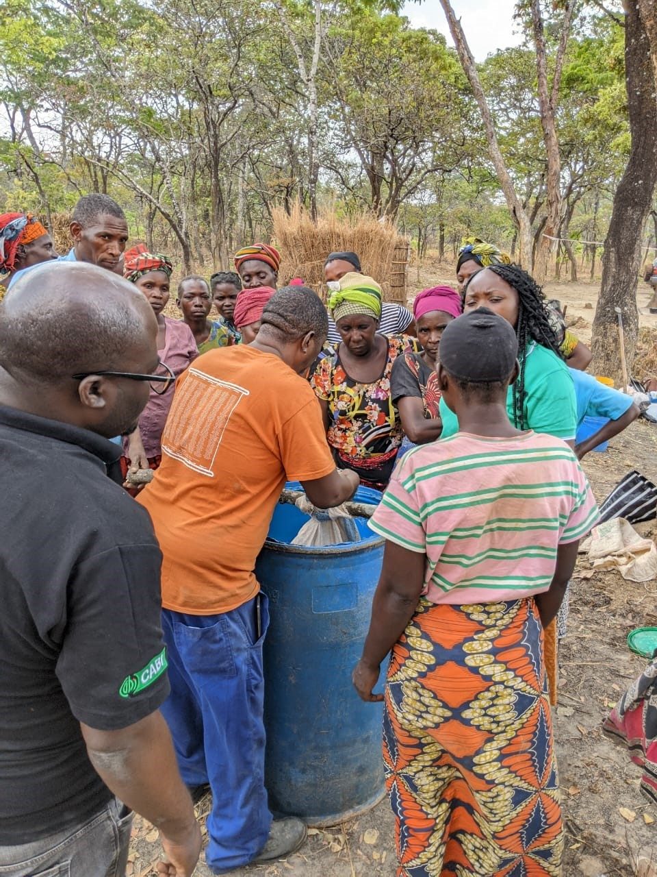 Community members gathered around a blue water drum